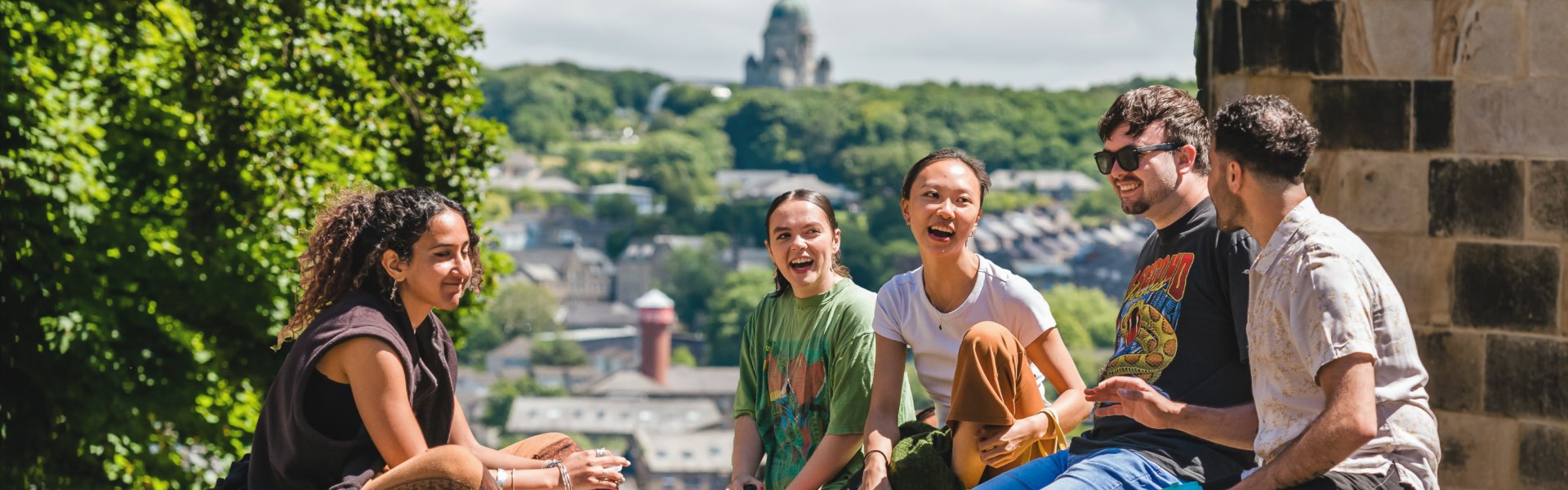 A group of students are seated by the castle overlooking the city.