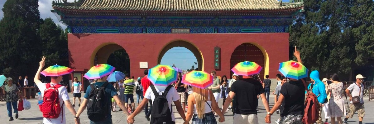 Students with rainbow-coloured hats in front of a traditional Chinese building.